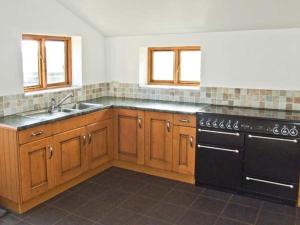 cocina con armarios de madera y lavavajillas negro en The Stables en Edale