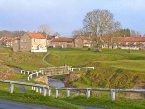 a bridge over a river with houses in the background at Brookleigh in Hutton le Hole