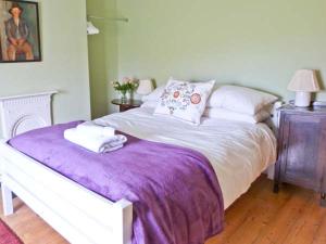 een slaapkamer met een groot bed en een paarse deken bij Brookleigh in Hutton le Hole