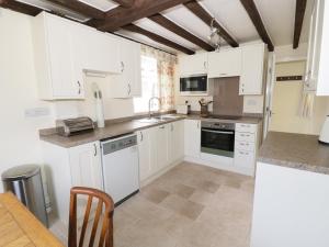 a kitchen with white cabinets and a sink and a table at Causeway Cottage in Pencombe