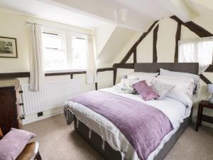 um quarto com uma cama grande com lençóis roxos e uma janela em Causeway Cottage em Pencombe
