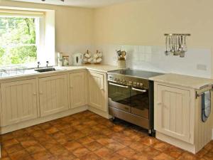 a kitchen with a stove and a sink and a window at Bryn Cemlyn in Llanfachreth