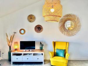 uma sala de estar com uma televisão e uma cadeira amarela em Apartment Elaura by Interhome em Biarritz