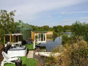 een huis met een terras en een boot op het water bij Secret Island Yurt in Beckford