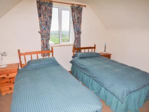 two beds in a room with a window at Colbha Cottage in Portsalon