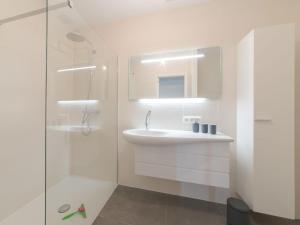a white bathroom with a sink and a shower at Apartment Lakeside by Interhome in Bredene