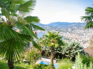 a view from the garden of a villa with palm trees at Holiday Home Nido di Rondine-1 by Interhome in Viganello