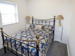a bedroom with a bed with a blue and white comforter at 3 Primitive Croft in Chelmorton