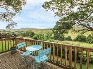 a deck with two chairs and a table on it at Byre Cottage in Alston