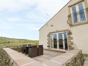 eine Terrasse mit Stühlen und ein Gebäude in der Unterkunft Meadow Cottage in Keighley