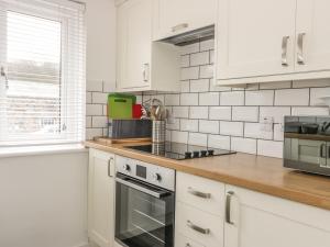 a kitchen with white cabinets and a stove top oven at On The Beach in Spittal