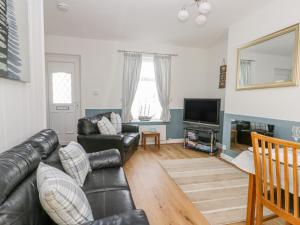 a living room with a leather couch and a television at Sea Breakers Cottage in Filey