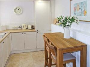 a kitchen with a table and a vase with flowers on it at Kipper's Corner in Doveridge