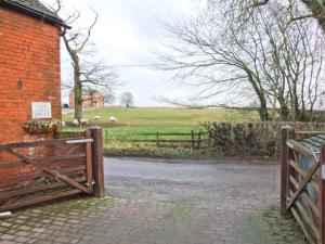 a gate to a brick building with a field with sheep at Kipper's Corner in Doveridge