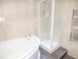 a white bathroom with a shower and a tub at Arfryn in Bethesda