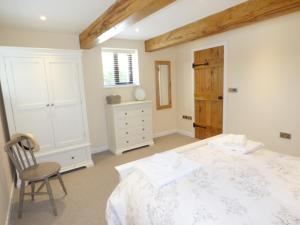 una camera con letto, sedia e cassettiera di Brightley Mill Barn a Okehampton