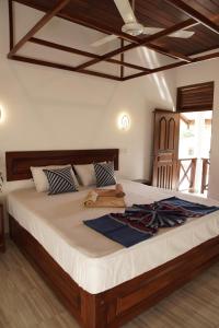 1 dormitorio con 1 cama grande y cabecero de madera en Surf Nest Hiriketiya en Dikwella South