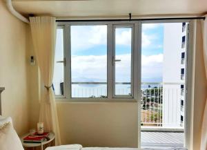 a bedroom with a large window with a view of the ocean at 1 BR Cozy Farmhouse-Style Condo with Balcony & Taal View at Wind Residences in Tagaytay