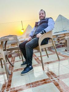 een man in een stoel in een kamer bij Happy days Pyramids Inn in Caïro