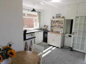 cocina con armarios blancos, mesa y ventana en Alberts Lodge en Boultham