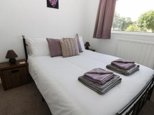 Una cama blanca con toallas apiladas encima. en Alberts Lodge en Boultham