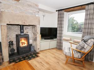 a living room with a fireplace and a tv at Bank Cottage in Bradwell
