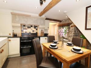 a kitchen with a wooden table with chairs and an oven at Bank Cottage in Bradwell