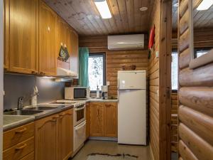 uma cozinha com armários de madeira e um frigorífico branco em Holiday Home Teeri by Interhome em Urimolahti