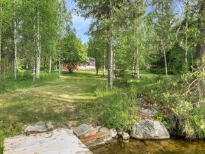 eine Brücke über einen Bach in einem Park mit Bäumen in der Unterkunft Holiday Home Teeri by Interhome in Urimolahti