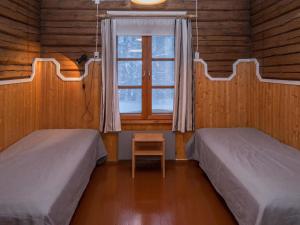 two beds in a room with a window and a chair at Holiday Home Palokärki by Interhome in Urimolahti