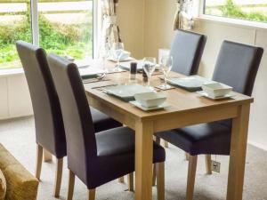 Whorlton Lodge في Potto: طاولة خشبية بأربعة كراسي وطاولة مع كؤوس للنبيذ
