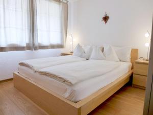 una camera da letto con un grande letto bianco con cuscini bianchi di Apartment Laerchehus Ost by Interhome a Kandersteg