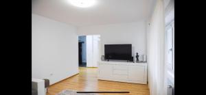 a white living room with a television on a dresser at Vlaicu Residence in Iaşi