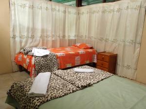 a room with two beds and a window with curtains at Villa Hermosa de Tambopata Casa Hospedaje & Hostel in Puerto Maldonado