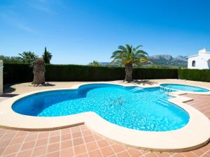 a swimming pool in the middle of a patio with palm trees at Holiday Home Peeters by Interhome in Calpe