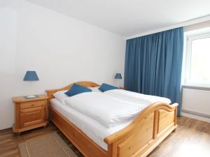 una camera da letto con letto in legno con tende blu e finestra di Apartment Isolde by Interhome a Reith bei Seefeld