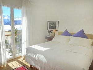 a bedroom with a large white bed with blue pillows at Apartment Chesa Sur Puoz 7 by Interhome in Samedan