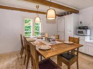 a dining room with a wooden table and a kitchen at Holiday Home Villa nennebo by Interhome in Förby