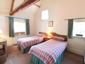 two beds in a room with two windows at Henhouse Cottage in Gillamoor