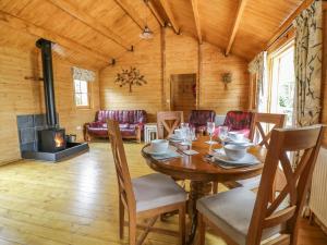 ein Esszimmer mit einem Tisch und einem Kamin in der Unterkunft Acorn Lodge in Saxmundham