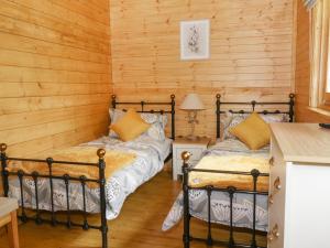2 Betten in einem Zimmer mit Holzwänden in der Unterkunft Acorn Lodge in Saxmundham