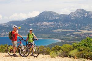 deux personnes debout sur une colline avec leurs vélos dans l'établissement Feriendorf zum störrischen Esel, à Calvi