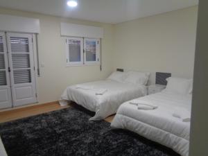 2 Betten in einem Zimmer mit weißen Wänden und Fenstern in der Unterkunft Apartamento VI-ANA in Viana do Castelo