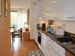 une cuisine avec des placards blancs, une table et un comptoir dans l'établissement Apartment Chesa San Bastiaun B4 by Interhome, à Samedan