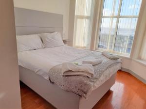 a bedroom with a bed with white sheets and windows at Skye Oceans Hotel in Blackpool