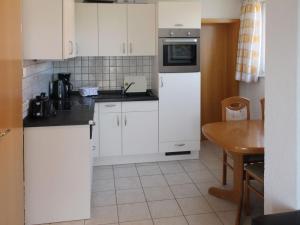 une cuisine avec des placards blancs et une table dans l'établissement Apartment FIP-Ferienpark - Insel Poel-1 by Interhome, à Gollwitz