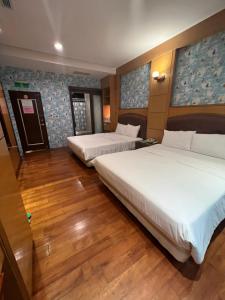 two beds in a hotel room with wooden floors at Charming Motel in Hualien City