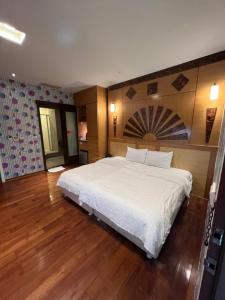 - duże białe łóżko w pokoju z drewnianą podłogą w obiekcie Charming Motel w mieście Hualian