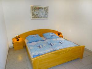 a bedroom with a wooden bed with blue pillows at Apartment Gollwitzer Park - Insel Poel-9 by Interhome in Gollwitz