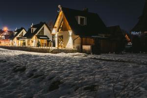 una calle nevada frente a las casas por la noche en Osada Białka Tatrzańska - apartamenty & domki z ogrodem dla rodzin Odkryj-Bialke, en Białka Tatrzanska